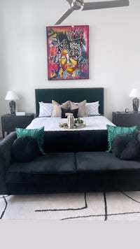 a bedroom with a black couch and a painting on the wall