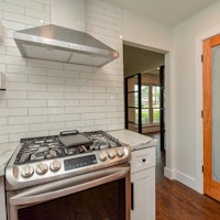 a kitchen with a stove and a wooden door