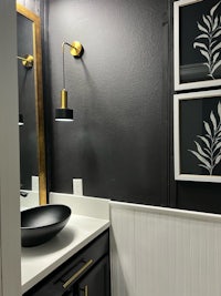 a bathroom with black walls and gold accents