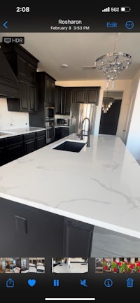 a photo of a kitchen with black cabinets and marble counter tops