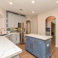 a kitchen with white cabinets and blue counter tops