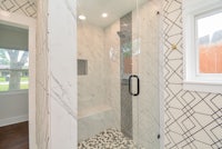 a black and white tiled shower with a glass door