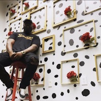 a man sitting on a stool in front of a polka dot wall