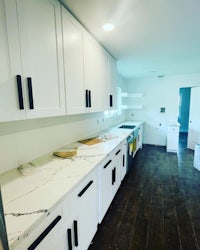a kitchen with white cabinets and marble counter tops