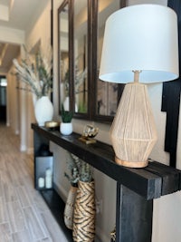 a console table with a lamp and vases on it