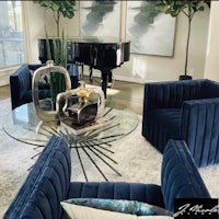 a living room with blue velvet chairs and a piano