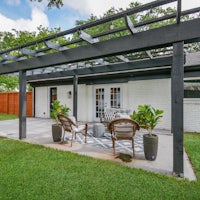 a backyard with a metal pergola and patio furniture