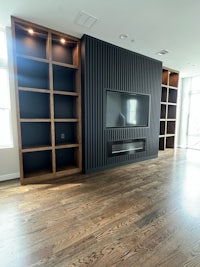 a living room with black bookshelves and a tv