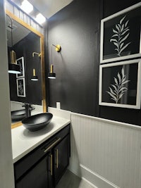 a bathroom with black walls and gold accents